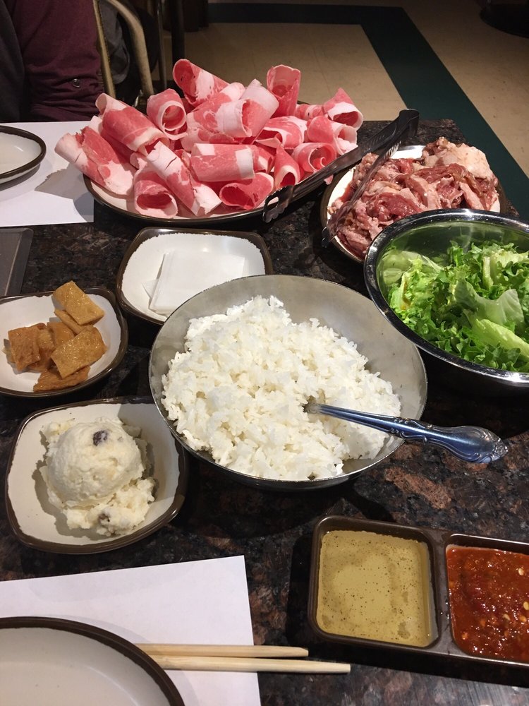 Plates of raw brisket, bulgogi and pork belly with rice, tofu and dipping sauces